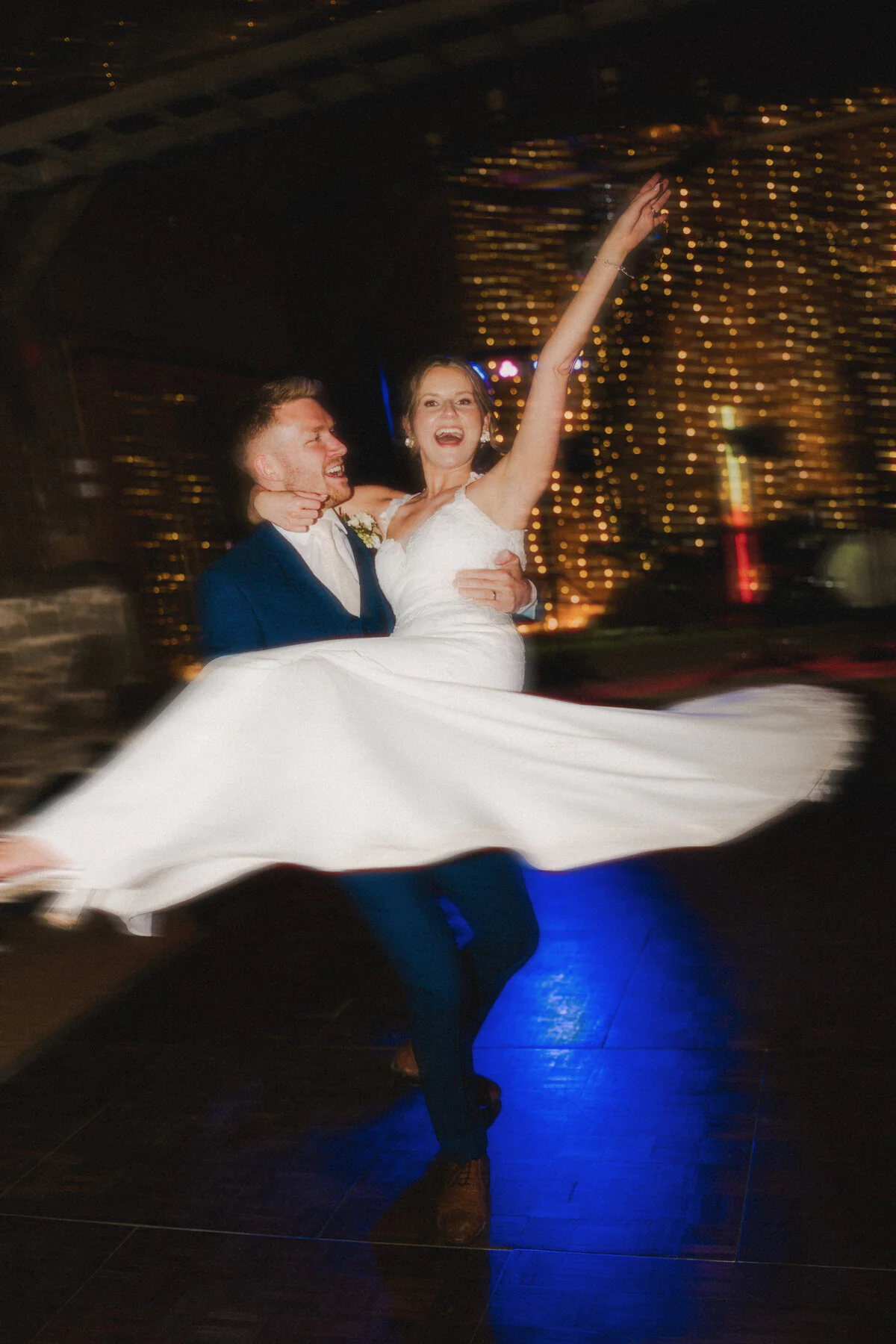 Ca104338 Edit Edit Groom lifting the bride while dancing at their evening wedding reception.