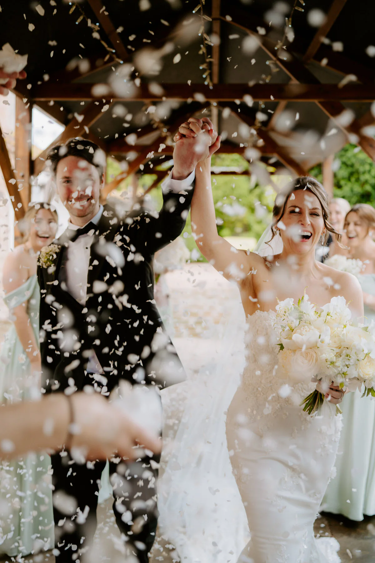 Charlie And Peter 308 Joyful newlyweds walking through wedding confetti after their ceremony.