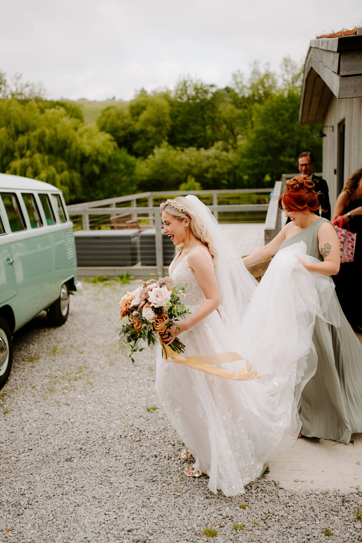 Dsc02923 Laughing bride in a lace gown holding an autumn bouquet beside a mint-green VW campervan.