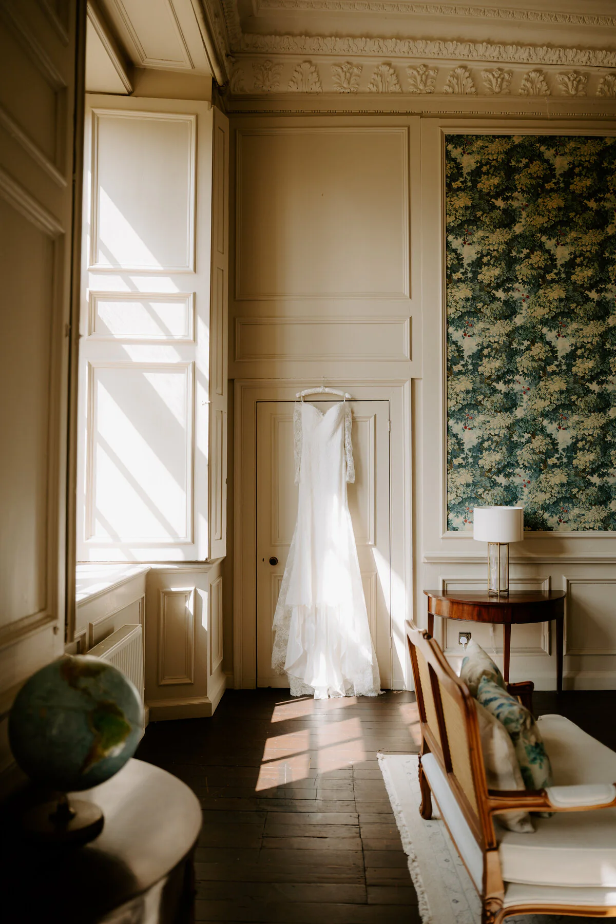 Dsc01216 Wedding dress hanging in a sunlit period room with panelled walls and a tapestry.