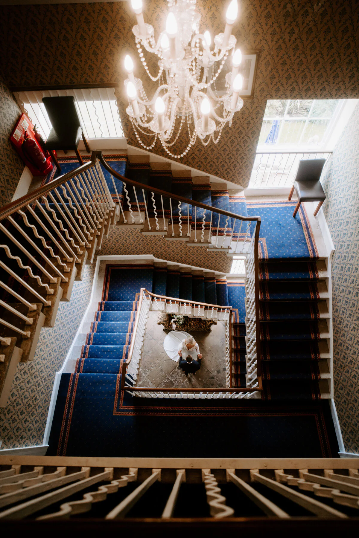 A7306496 393 17 Overhead view of a grand spiral staircase with blue carpet and a chandelier.