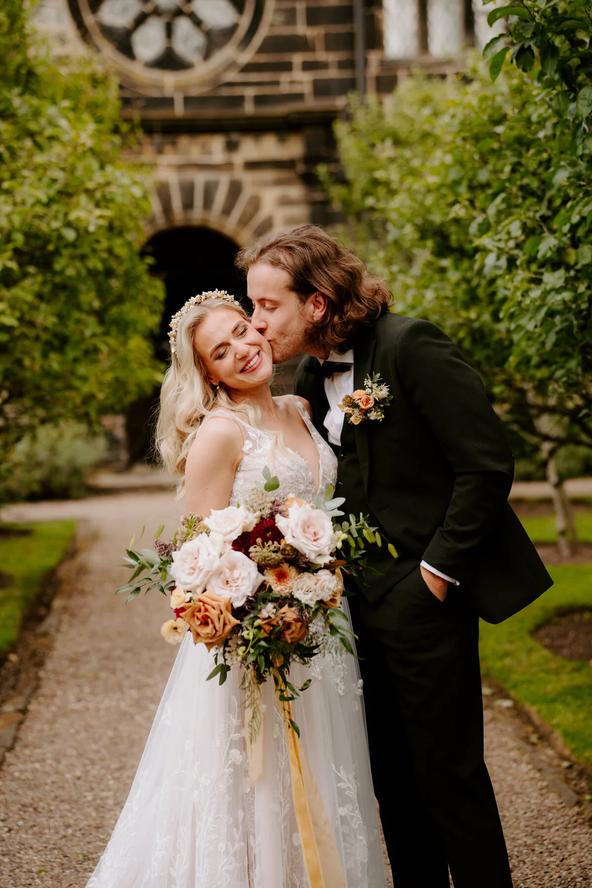 Dsc06658 Groom kissing the bride's cheek in a walled garden at a stone manor house.