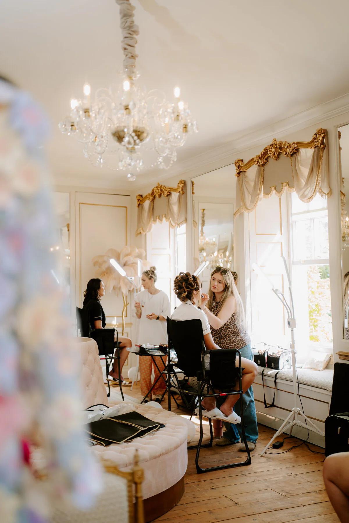Dsc08564 Makeup artist applying bridal makeup in an ornate chandelier-lit manor room.