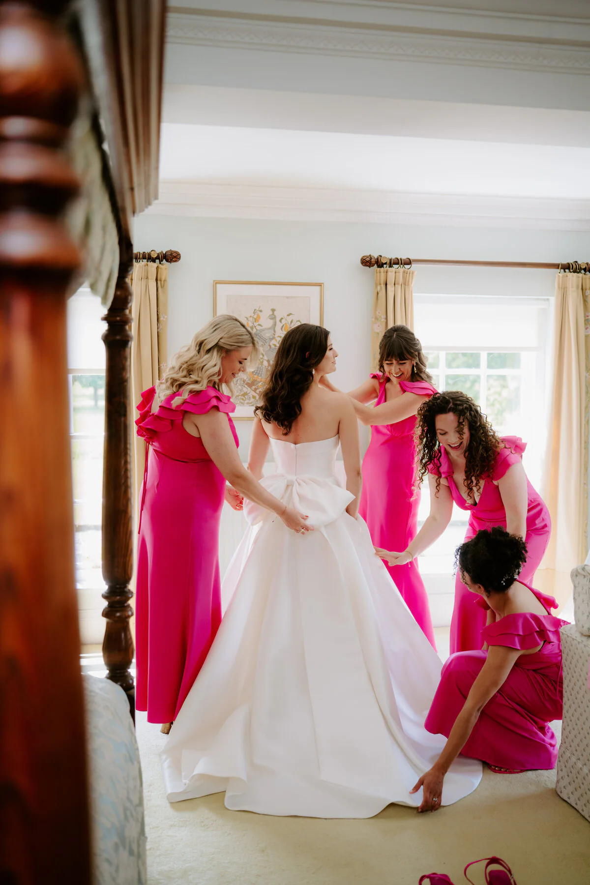 Dsc07624 Bridesmaids in hot-pink dresses helping the bride into her bow-back ballgown.