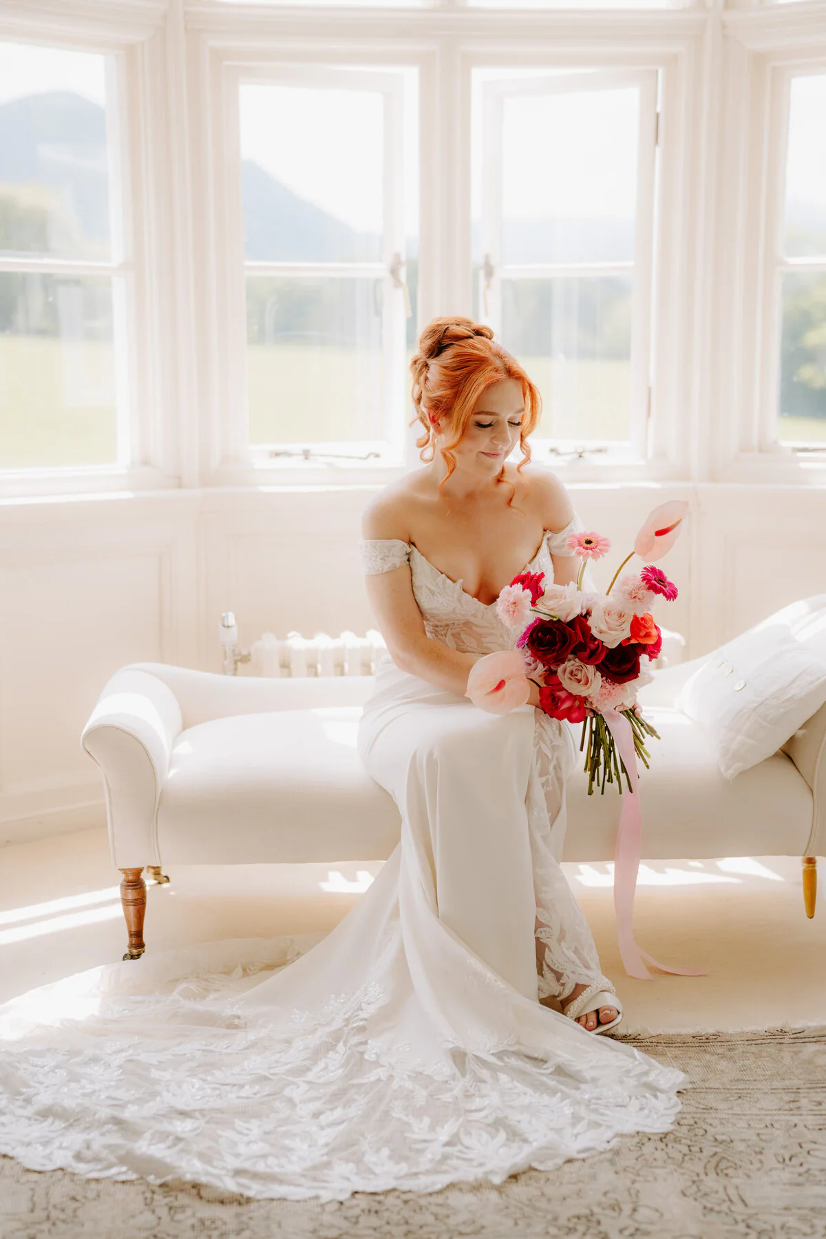 Dsc03975 Red-haired bride on a chaise longue with red and pink flowers by a bay window.