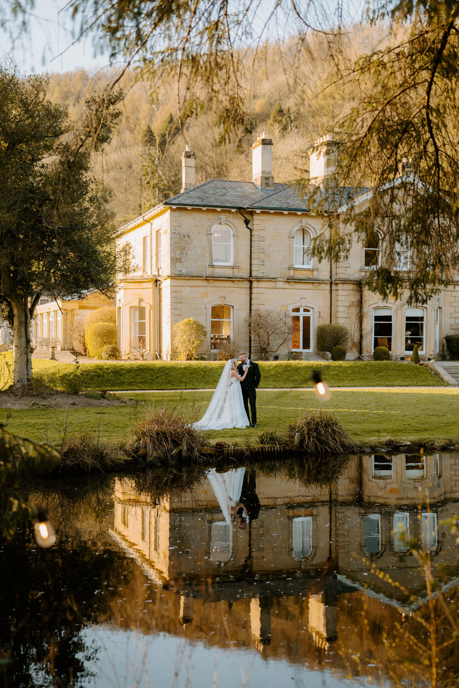 Lace wedding gown hanging beside an antique carved French wardrobe mirror
