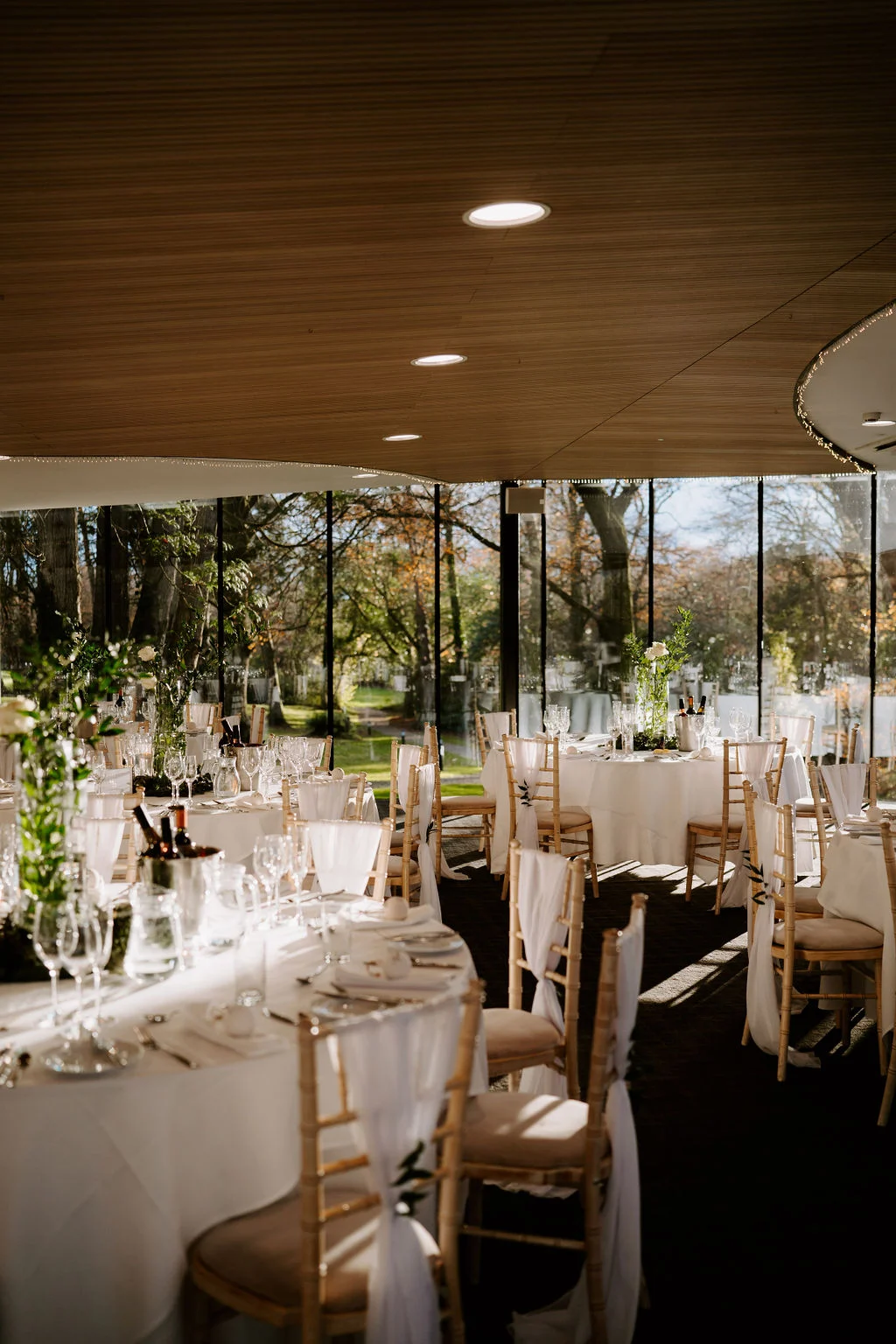 Wedding reception tables and glass walls looking towards woodland at Fairyhill