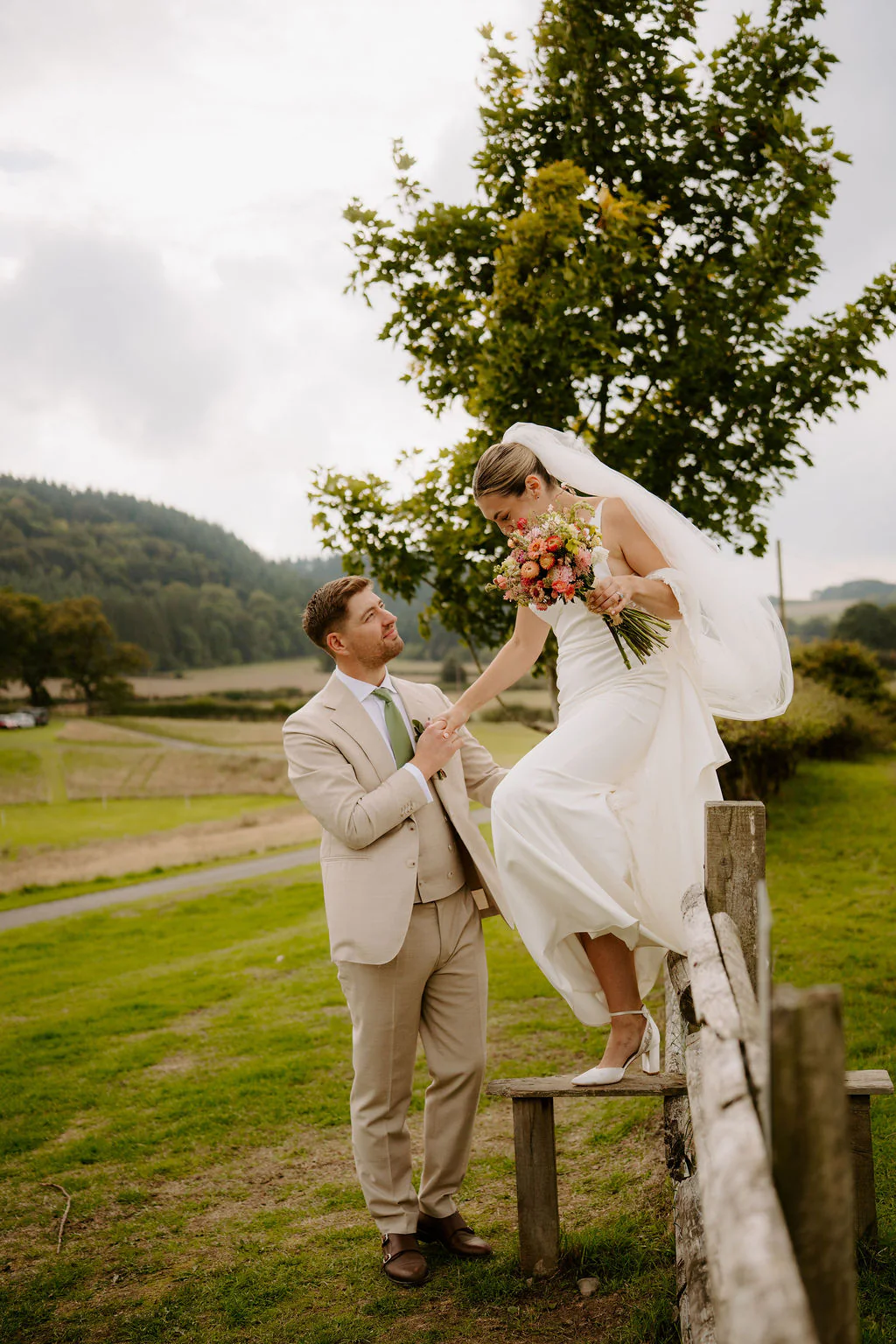 Wilde Lodge Wedding Videographer & Photographer | Ludlow Alice & Matthew walking hand-in-hand through the wild flower meadows at Wilde Lodge