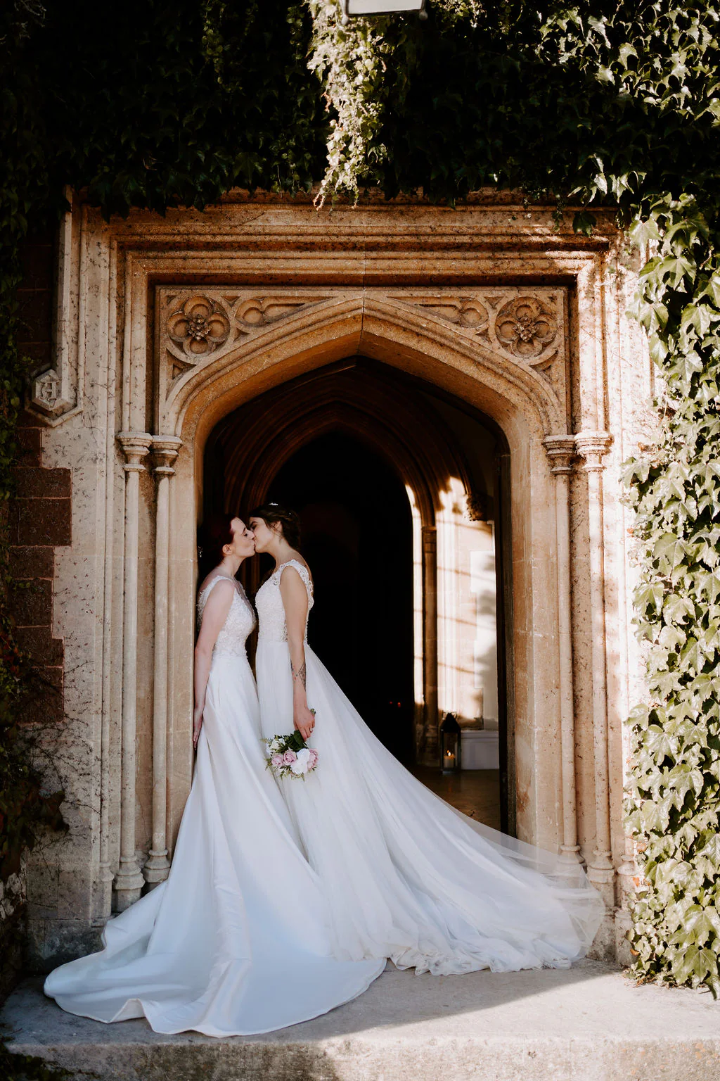 St Audries Park Wedding Photography & Film | Quantock Hills Jodie & Natalie romantic couple portrait kissing in the historic stone door arch at St Audries Park in Quantock Hills